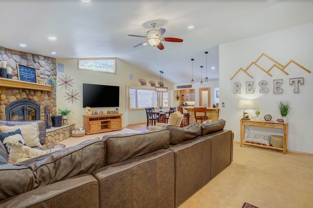 Open-concept living and dining area with stone fireplace and RESET mountain wall art
