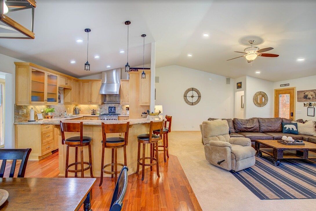 Kitchen island with bar stools opening to the living room with recliner and leather sectional