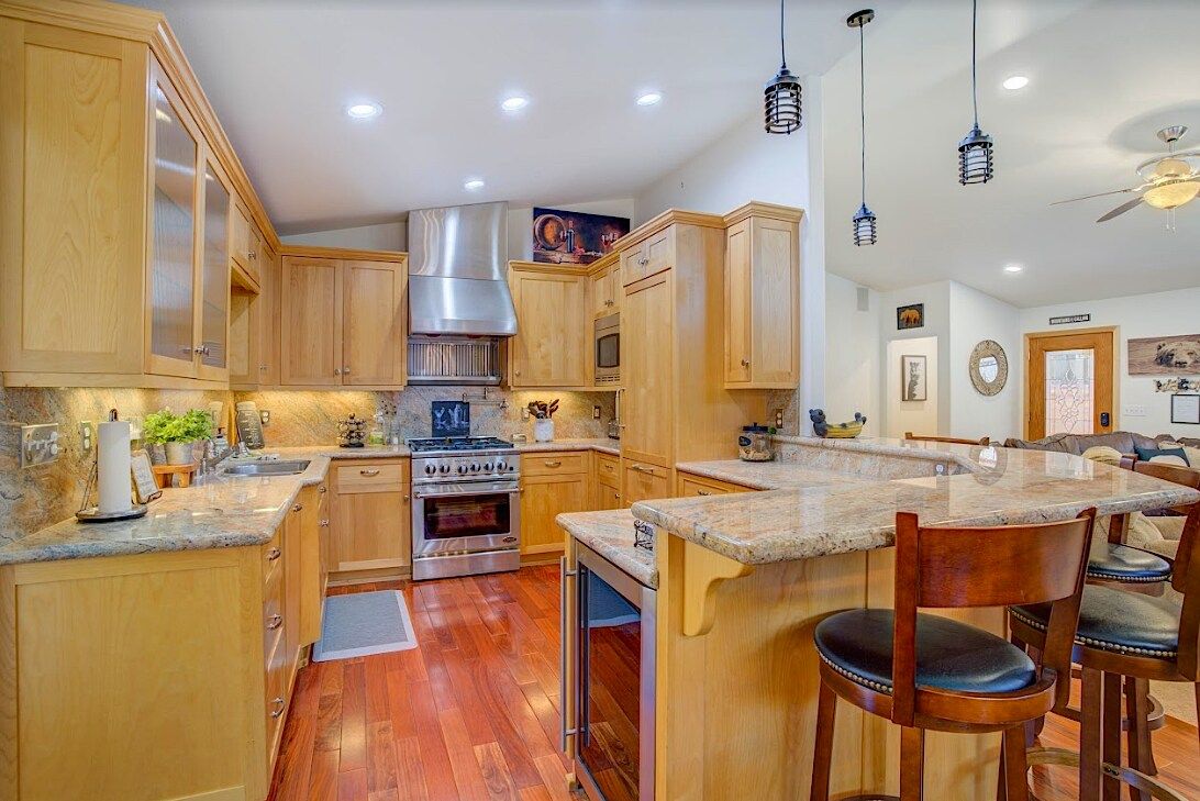 Kitchen with breakfast bar, pendant lighting, wine fridge, and view to the living room