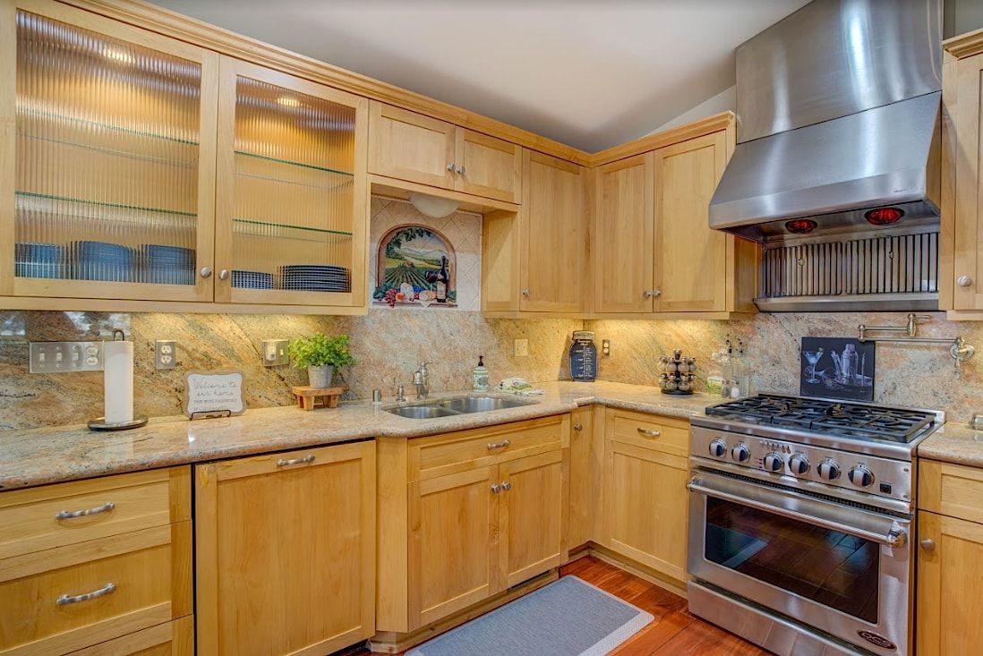 Kitchen detail with gas range, granite countertops, and glass-front cabinets