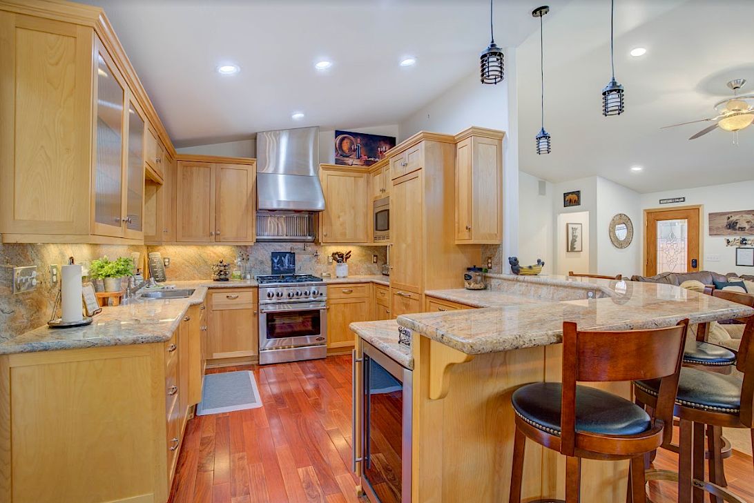 Gourmet kitchen with maple cabinets, granite countertops, stainless steel gas range, and breakfast bar with stools