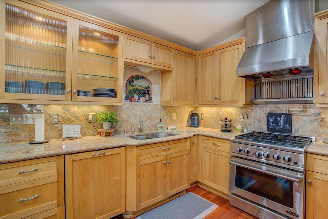 Kitchen detail with glass-front cabinets, farmhouse sink, gas range, and granite countertops