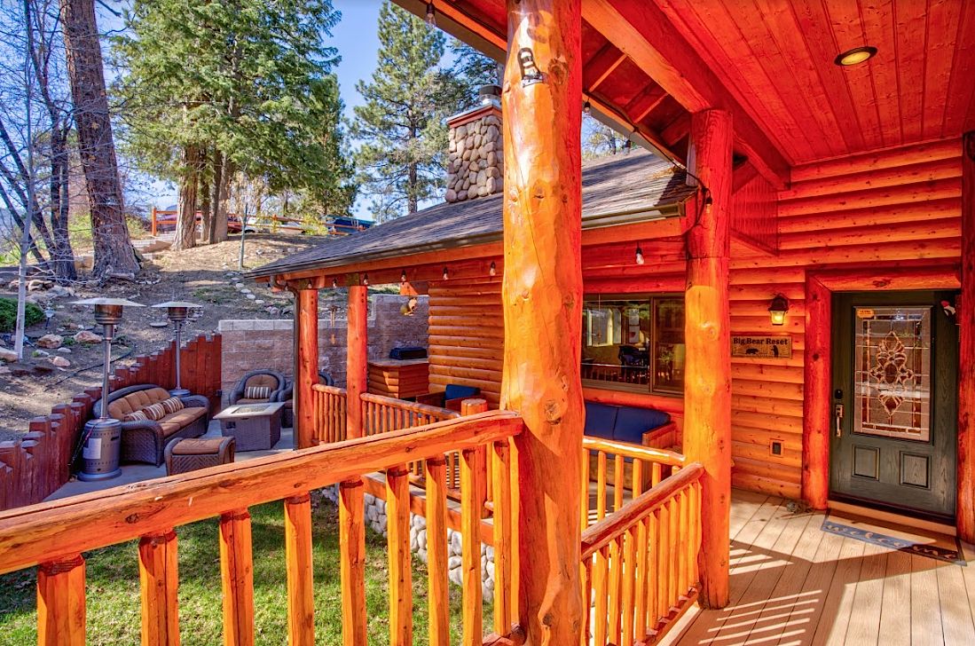Front porch with log railings and 'Big Bear Reset' sign by the entrance door