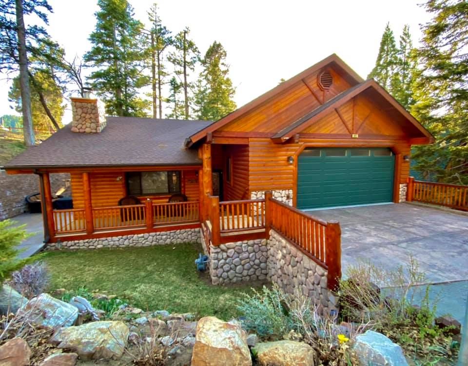 Big Bear Reset log cabin exterior with garage, covered porch, and stone chimney